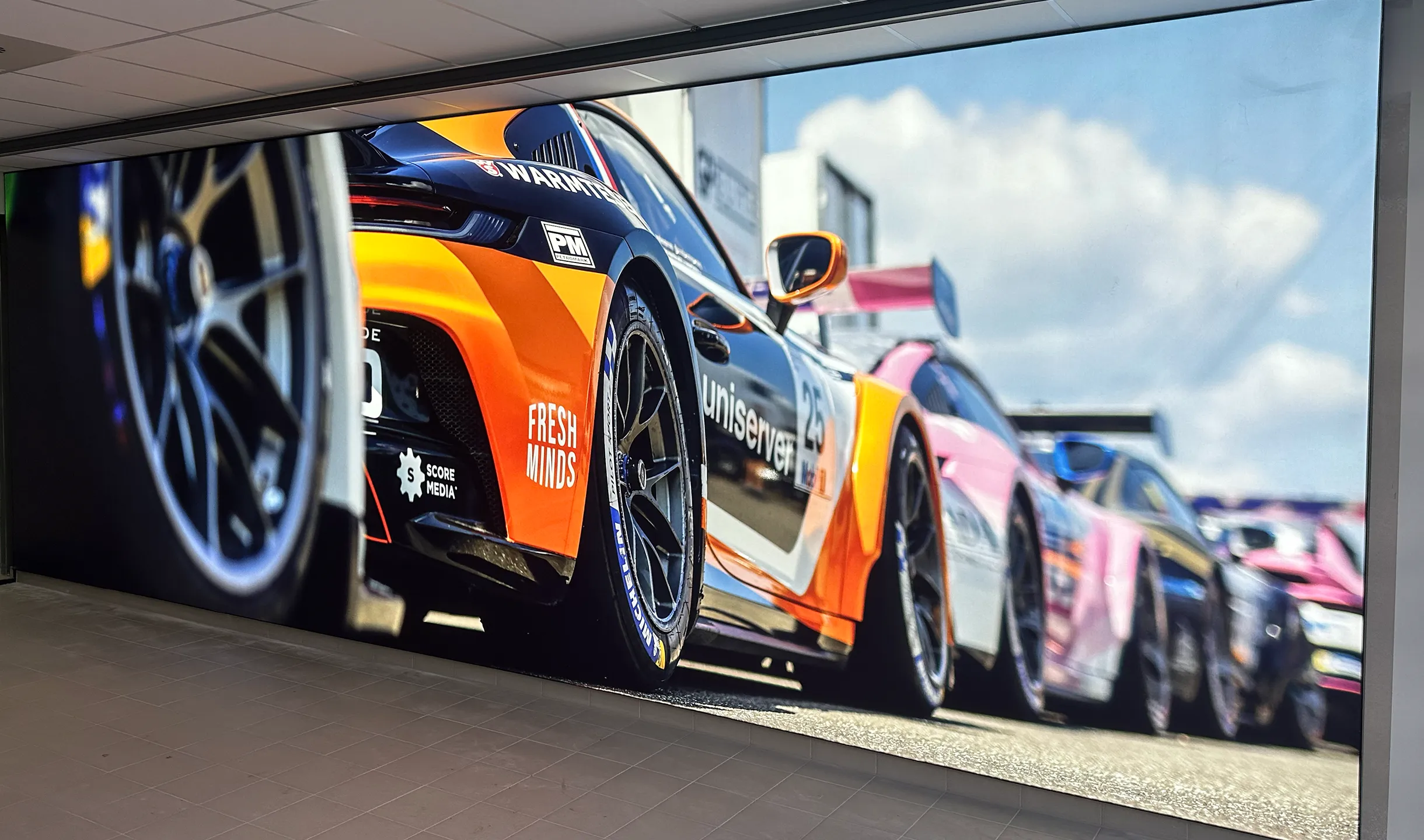 Een foto van een ledscherm dat RW Projecten heeft gemonteerd. Op het scherm zie je een aantal Porsche auto's.